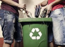 two people recylcing electronics into a bin