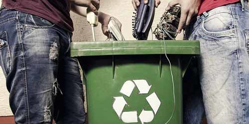 two people recylcing electronics into a bin