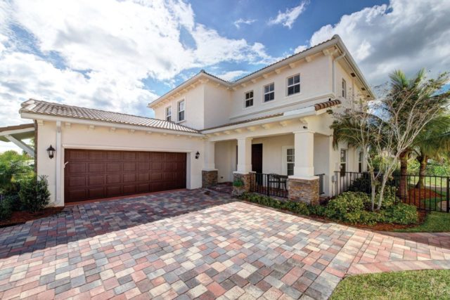 A modern, two-story house in Jupiter, FL with a large driveway and a two-car garage