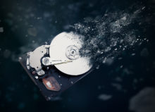 A hard drive with particles of data disintegrating and floating away from it, symbolizing data destruction.