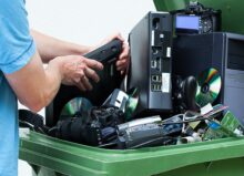 Man discarding old cds and dvd players in a recycling bin