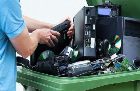 Man discarding old cds and dvd players in a recycling bin