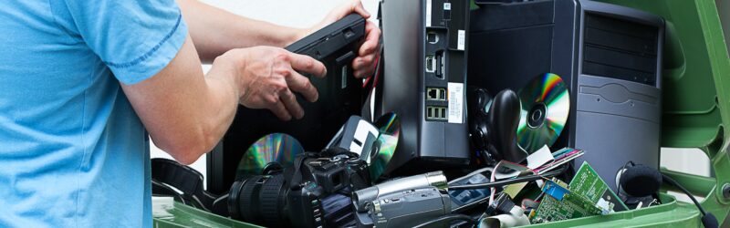 Man discarding old cds and dvd players in a recycling bin