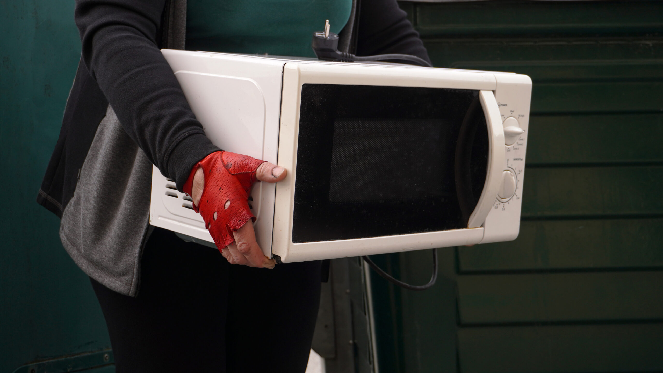 Woman carrying old microwave to recycle